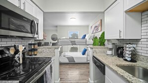 A modern kitchen with white cabinets, a black stove, and a coffee machine.