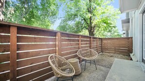 A wooden fence with two wicker chairs and a small table in a garden area.
