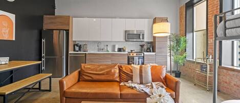 Comfortable studio with sofa, kitchen, dining table, and bunk bed for a relaxed stay.