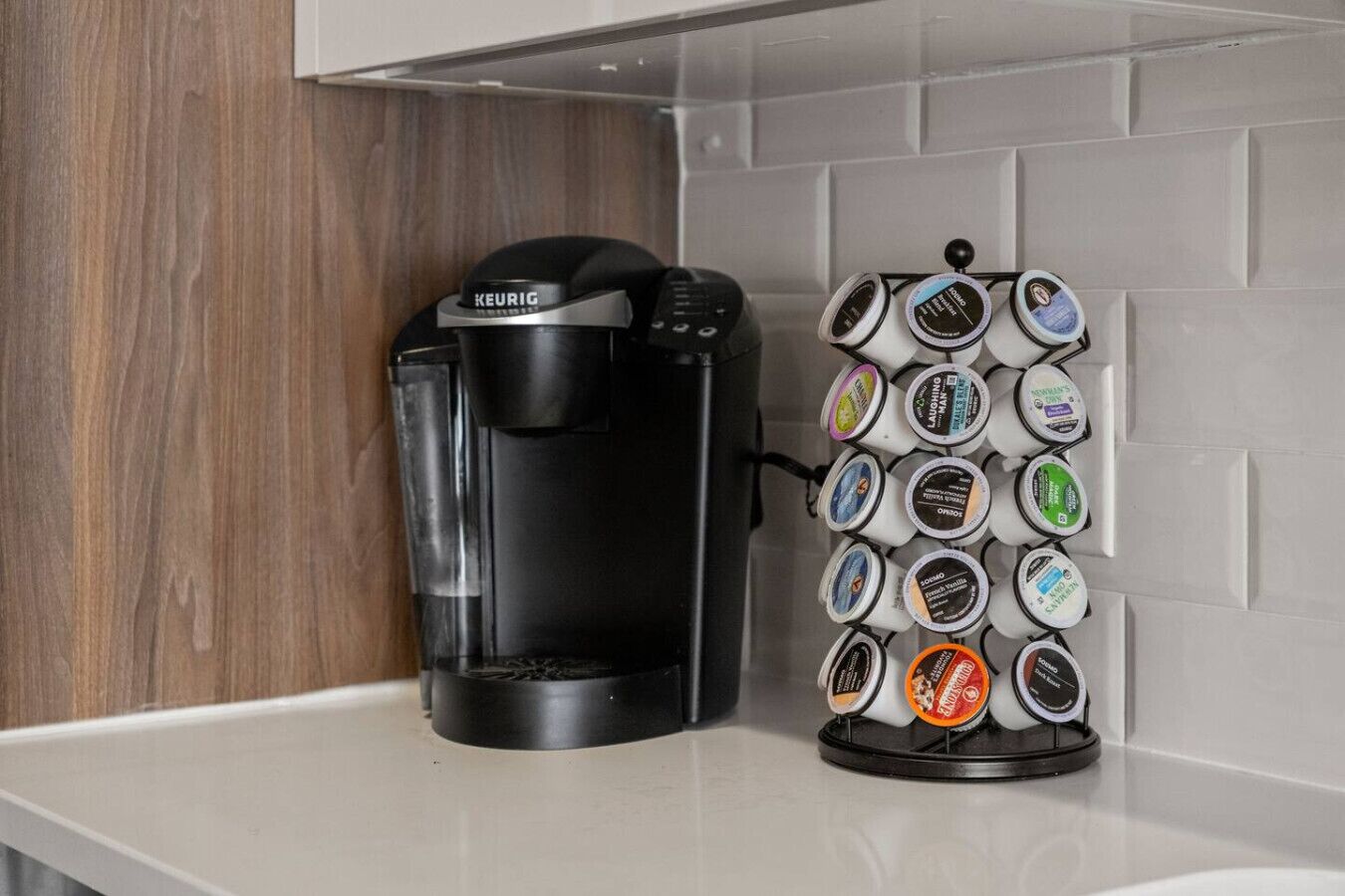 A Keurig coffee maker and a coffee pod holder with various flavors on a kitchen counter.