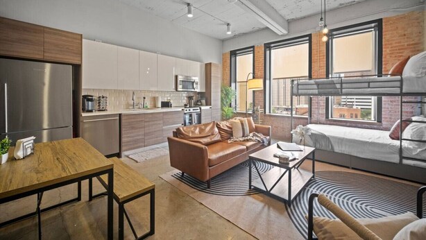 A modern apartment with a kitchen, living area, and a bunk bed.