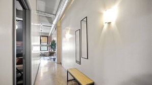 A hallway with a bench, framed pictures, and a light fixture.