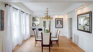 A dining area with a chandelier, white curtains, and a framed artwork on the wall. - 7BR The Athena! Luxury Chef's Kitchen in Montrose ★★★★★ (Houston)