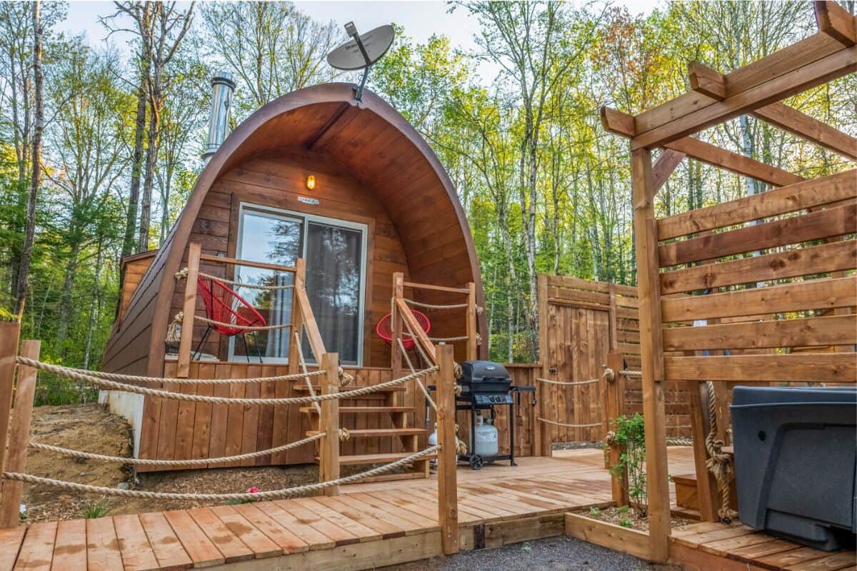 A wooden cabin with a satellite dish, a grill, and a rope fence.