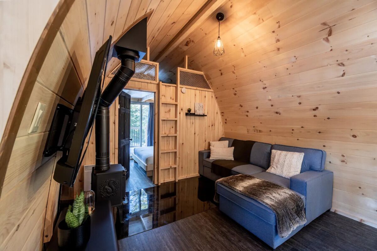 Un interior de cabaña acogedor con techo de madera, un sofá azul, una mesita y una chimenea.