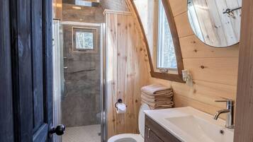 Baño de cabaña de madera con un lavamanos grande, inodoro y zona de ducha.
