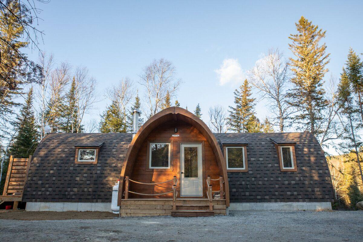 A wooden cabin with a large arched entrance, two windows on the side, and a small window above the door.