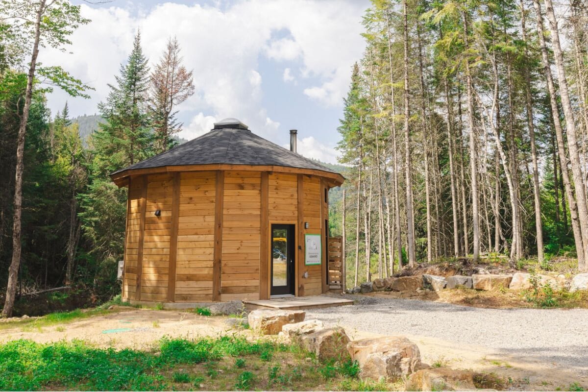 A wooden cabin with a circular roof, surrounded by trees.