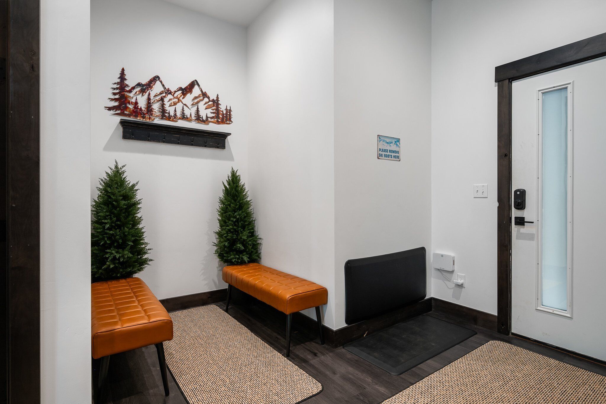 A reception area with two wooden benches, a small Christmas tree, a decorative wall piece, a sign, and a door with a light switch.