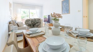 A dining area with a wooden table set for a meal, white plates, and clear glasses. - Bright Bay Calanova Grand Golf (Mijas Costa)