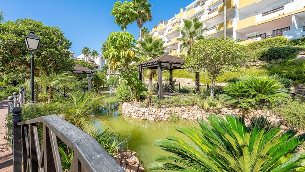 A lush garden with a pond, palm trees, and a gazebo. - Bright Bay Calanova Grand Golf (Mijas Costa)