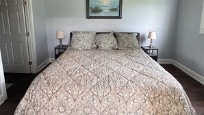 Een slaapkamer met een bed, een plafondventilator, een schilderij aan de muur en twee bedlampen.