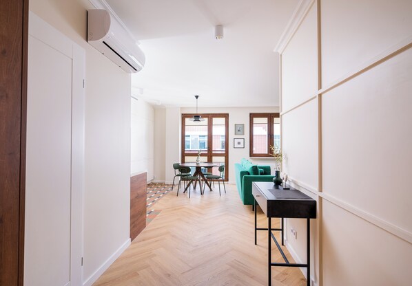 Un interior moderno con comedor, sofá verde y suelo de madera en espiga.
