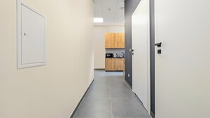 Een gang met een kitchenette aan het einde, voorzien van kastjes en een magnetron.
