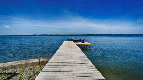 A wooden pier extending into a calm lake with a boat docked at the end. - Idle Hour: "Stunning Panoramic Views of Cayuga Lake!" (Ovid)