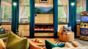 A cozy cabin interior with a wooden ceiling, a fireplace, a couch, and a table with a plate of food.