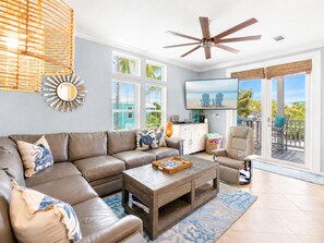 A living room with a sectional sofa, a coffee table, and a television mounted on the wall.