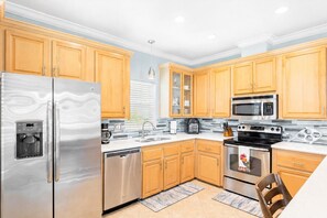 A modern kitchen with stainless steel appliances, wooden cabinets, and a tiled backsplash. - Private Florida Keys Escape w/ Pool, Dock, Tiki Bar – Pet Friendly (Little Torch Key)