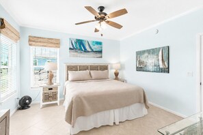 A bedroom with a bed, a ceiling fan, a window with blinds, and artwork on the walls. - Private Florida Keys Escape w/ Pool, Dock, Tiki Bar – Pet Friendly (Little Torch Key)