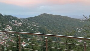Vista panorámica de una zona montañosa con edificios dispersos y una colina boscosa.