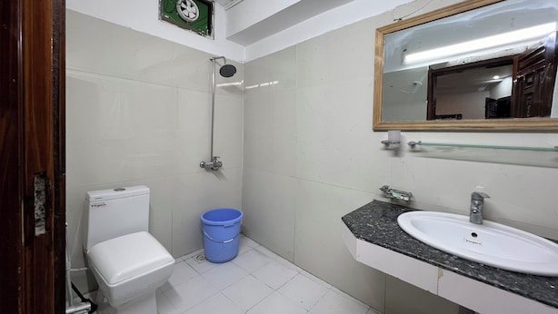 Un baño con inodoro, ducha, lavabo y espejo.