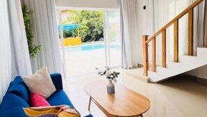 Ein modernes Wohnzimmer mit einem blauen Sofa, einem Holztisch und einer Treppe, die zu einer oberen Etage führt.