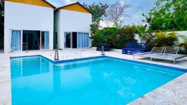 Ein Swimmingpool mit glasklarer blauer Wasseroberfläche, umgeben von einer Steinterrasse.