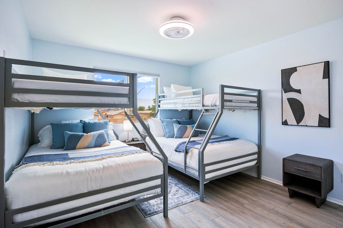 A room with bunk beds, a small bedside table, and a wall-mounted artwork.