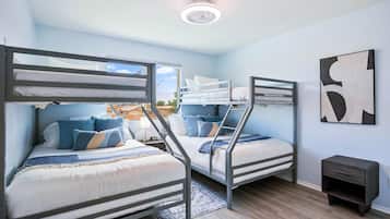 A room with bunk beds, a small bedside table, and a wall-mounted artwork.