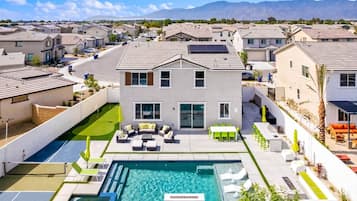 A residential area with a swimming pool, outdoor seating, and a view of mountains.