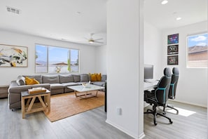 A modern living room with a grey sofa, a coffee table, and a desk with gaming chairs. - Margaritaville | Pickleball, Pool+Spa, GameRoom! (Coachella)