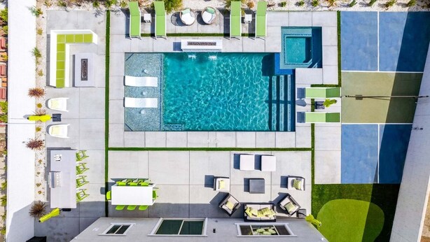 A rooftop swimming pool with multiple seating areas and a tennis court.