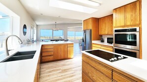 A modern kitchen with wooden cabinets, stainless steel appliances, and a large island. - Ocean Front on the Beach! Dog Friendly! (Waldport)