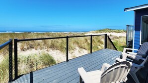 A deck with a view of the beach and ocean, featuring a table and chairs. - Ocean Front on the Beach! Dog Friendly! (Waldport)