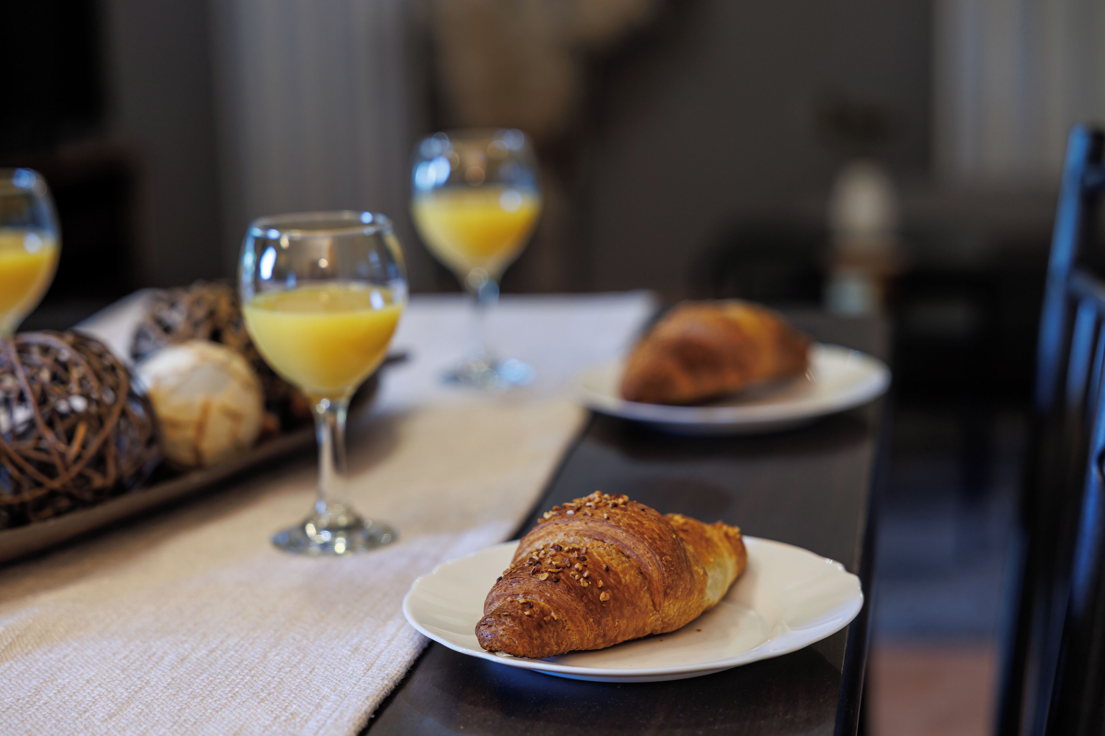 Una mesa con croissants y zumo de naranja para el desayuno.