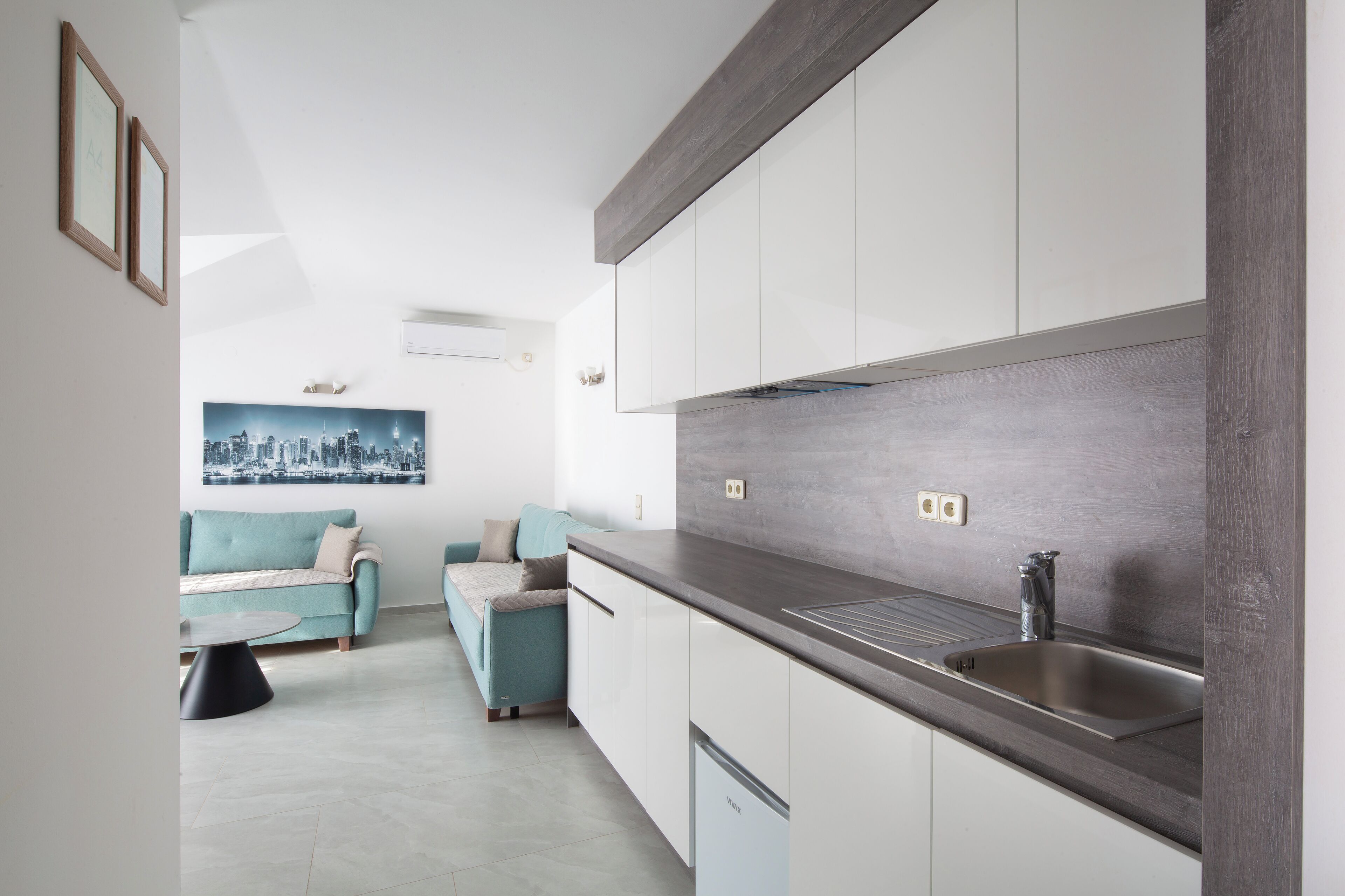 A modern kitchen with white cabinets, a dark countertop, and a stainless steel sink.