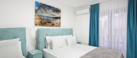 A hotel room with a bed, a nightstand, a painting, and a window with curtains.
