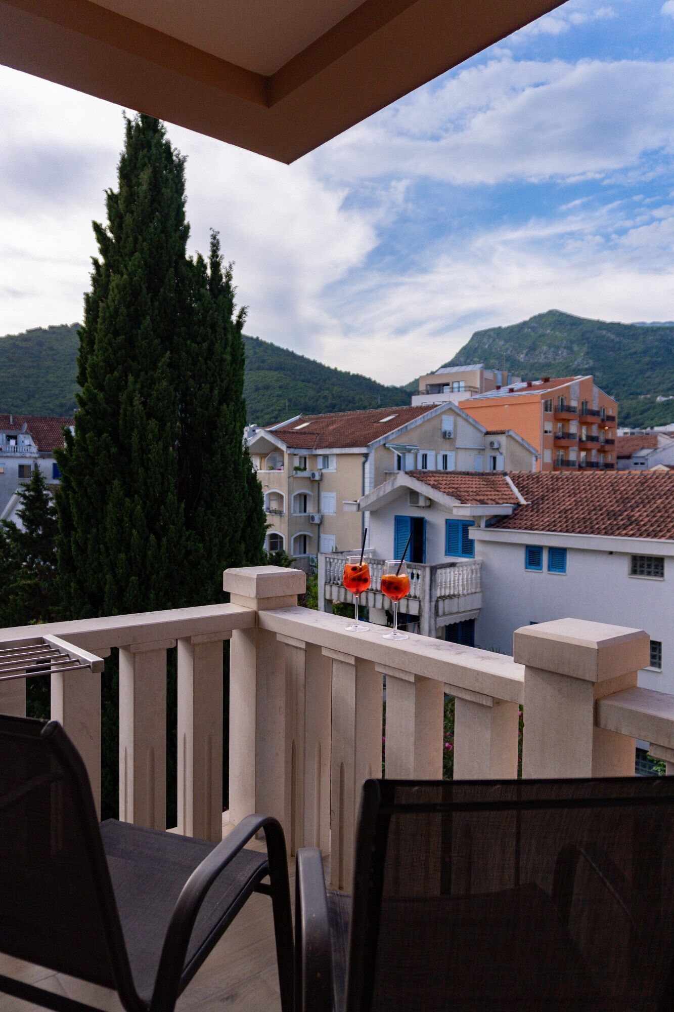 A balcony with a view of residential buildings and a mountain in the background.