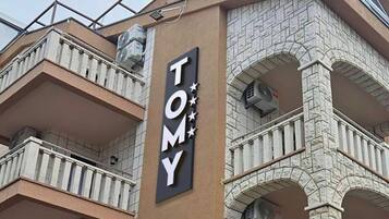 Un edificio con un letrero que dice "TOMY" y una fachada de piedra con balcones.