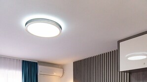 Une chambre d’hôtel avec un grand lit, une table de chevet avec un miroir, un téléviseur à écran plat et un climatiseur fixé au mur.
