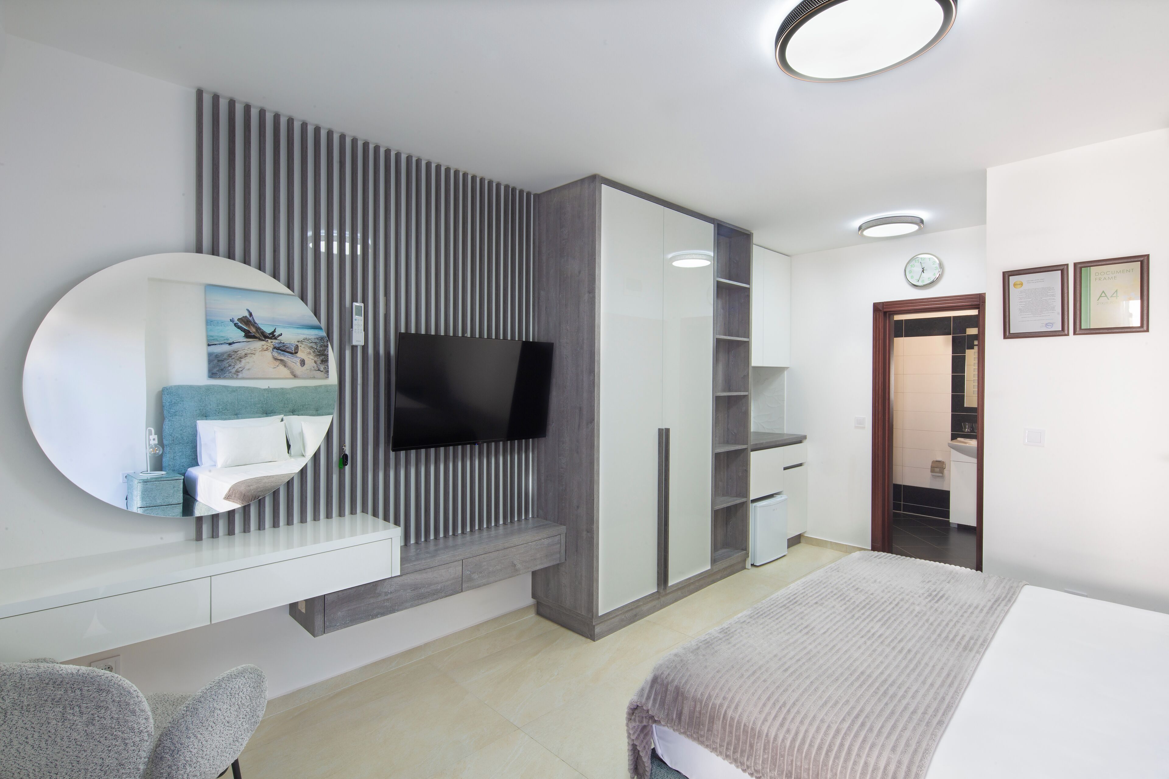 A modern bedroom with a large bed, a TV mounted on a wall, a bedside table, and a built-in wardrobe.
