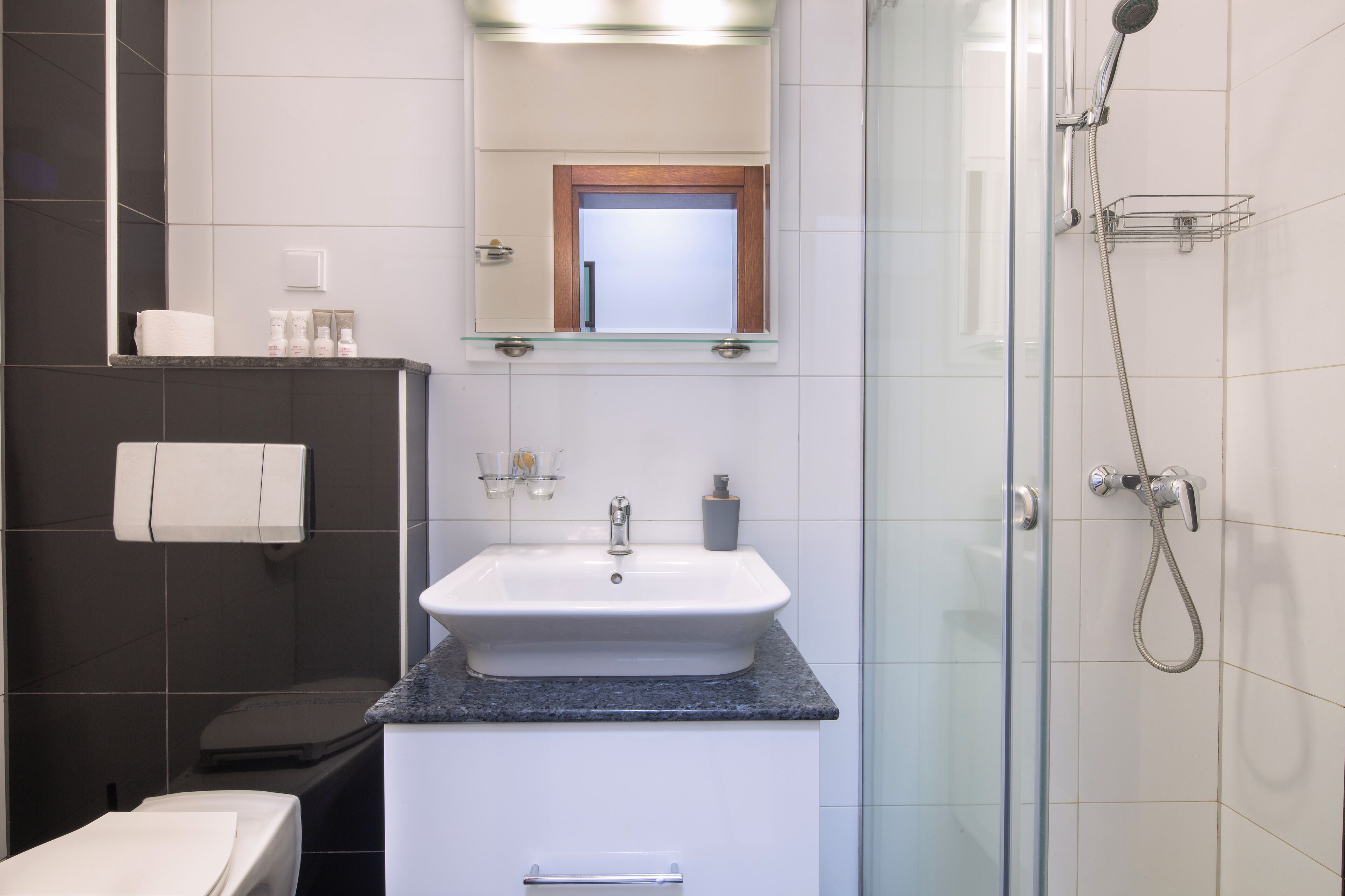 A bathroom with a white sink, a glass shower enclosure, and a mirror above the sink.