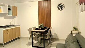A modern kitchen with a built-in stove, wooden cabinets, and a dining area with a table and chairs. - Apartamento cerca a la playa Punta Roca (Puerto Colombia)