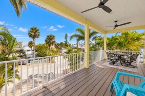 A wooden deck with outdoor furniture, a white railing, and palm trees. - 3BR/2BA Home | Pool, Ping-Pong & Beach Nearby! (Fort Myers Beach)