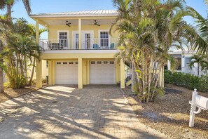 A two-story house with a covered porch, two garage doors, and a paved driveway. - 3BR/2BA Home | Pool, Ping-Pong & Beach Nearby! (Fort Myers Beach)