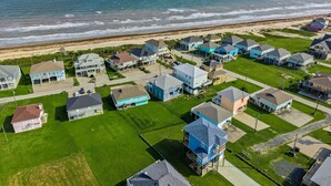 An aerial view of a coastal residential area with houses, a beach, and ocean.