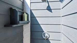 A shower area with a handheld showerhead and a wall-mounted faucet.