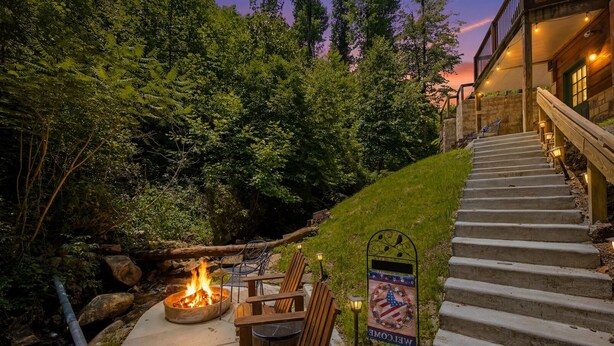 A fire pit with chairs, a welcome sign, and a staircase leading to a building.