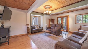 A spacious living room with wooden floors, a large sofa, a coffee table, and a fireplace.
