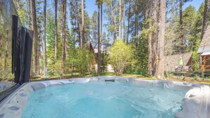 A hot tub surrounded by tall trees in a forested area.